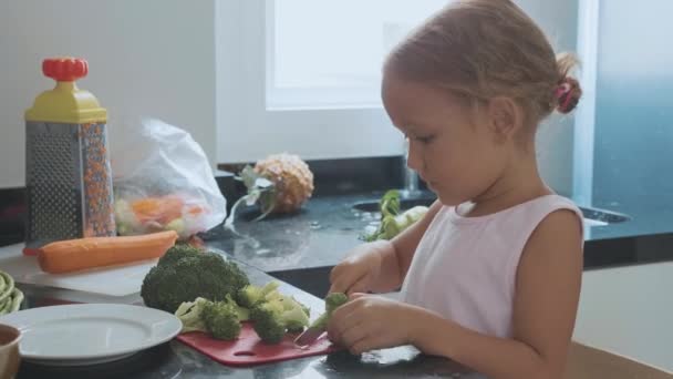 Μικρό παιδί κορίτσι κοπής brocoli για μαγείρεμα σε εγχώρια κουζίνα. — Αρχείο Βίντεο