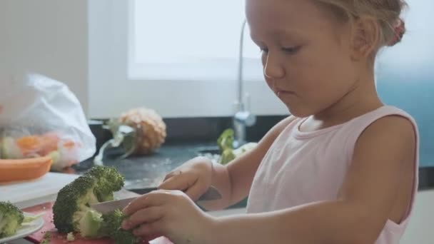 Μικρό παιδί κορίτσι κοπής brocoli για μαγείρεμα σε εγχώρια κουζίνα. — Αρχείο Βίντεο