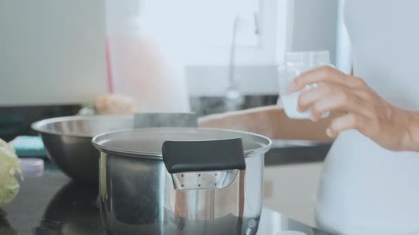 Vrouwelijke handen zouten kokende soep door lepel op binnenlandse keuken, close-up. — Stockvideo