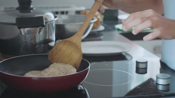 Молода жінка готує домашні бра на сковороді на домашній кухні — стокове відео