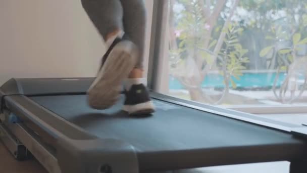 Sporty young woman running on treadmill, close-up feet rear view — Stock Video