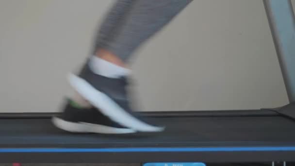 Sporty young woman running on treadmill, close-up feet rear view — Stock Video