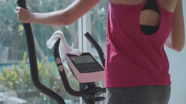 Mujer joven y deportiva haciendo ejercicio en la máquina de paso en el gimnasio condominio — Vídeo de stock