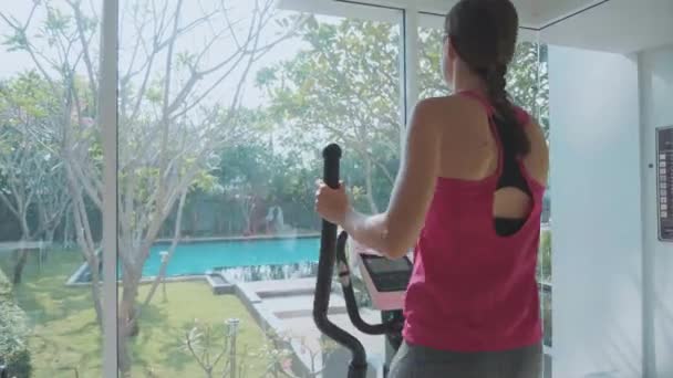 Mujer joven y deportiva haciendo ejercicio en la máquina de paso en el gimnasio condominio — Vídeo de stock