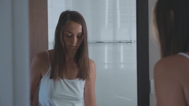 Jonge vrouw poetsen tanden met een tandenborstel in badkamer — Stockvideo