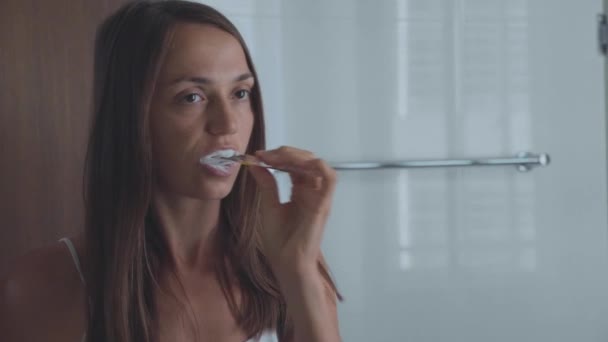 Mladá žena čištění zubů zubním kartáčkem v koupelně — Stock video