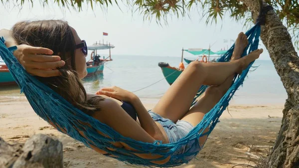 Joven mujer feliz tumbada en la hamaca en la playa de arena —  Fotos de Stock