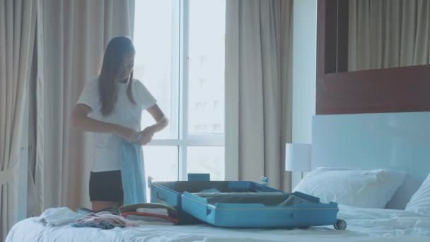 Молодая женщина собирает чемодан. Путешественник готовится к путешествию — стоковое видео