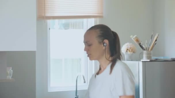 Ung kvinna dansar och sjunger medan matlagning på inhemska kök — Stockvideo