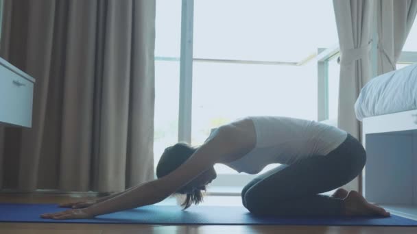 Giovane donna magra in tuta da allenamento facendo esercizio su mat indoor — Video Stock