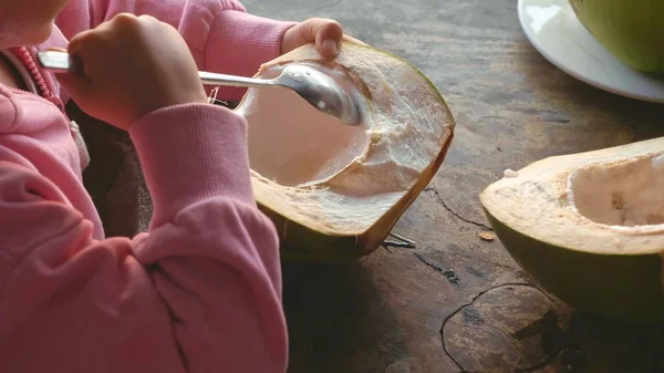 Niña linda comiendo coco por cuchara en la cafetería —  Fotos de Stock