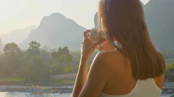 Mujer joven bebiendo café caliente en el balcón con hermoso paisaje de montaña — Foto de Stock