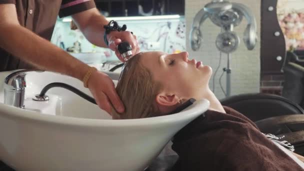 Mężczyzn stylista mycia blond womans głowę w nowoczesny salon kosmetyczny — Wideo stockowe