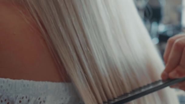 Männliche Friseur kämmt Haare zu blonden Mädchen in Schönheitssalon, Nahaufnahme — Stockvideo