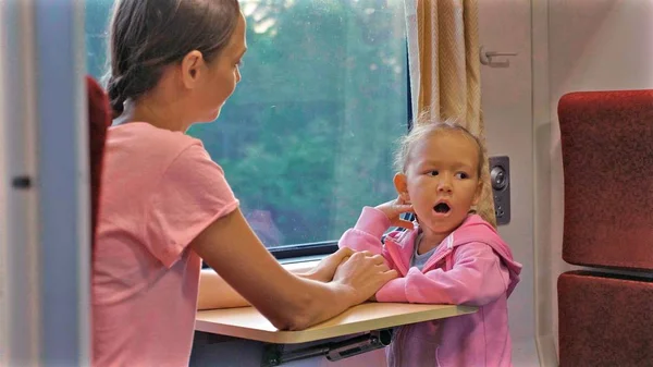Семья, проводящая время в поездке на поезде по Азии, глядя в окно и разговаривая — стоковое фото