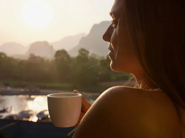 Young woman drinking hot coffee on the balcony with beautiful mountain landscape — Stock Photo, Image