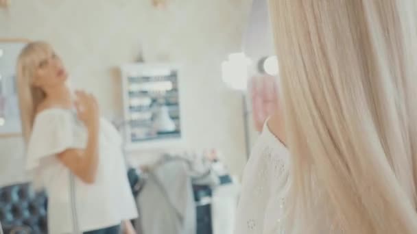 Mujer joven mirándose en el espejo y corrigiendo el peinado después del spa para el cabello — Vídeos de Stock