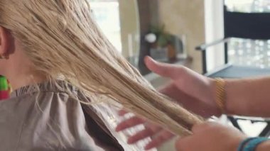 Kuaför olduğunu untangles sarışın kadın müşteri güzellik spa salonu saç