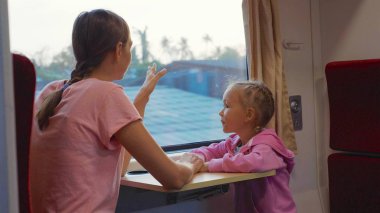 Aile Asya tren yolculuğunda zaman geçirmeden, pencereye bakıyor ve konuşmak