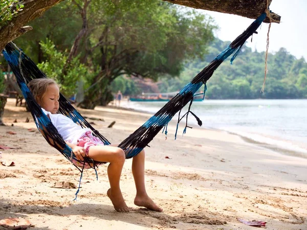 Linda niña acostada en la hamaca y relajarse en la playa de arena — Foto de Stock