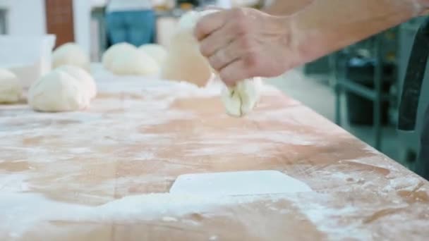 プロのパン屋はパン屋さんの厨房で生地の部分を形成します。. — ストック動画