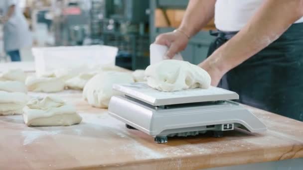 El panadero profesional divide la masa en porciones y las pesa — Vídeo de stock
