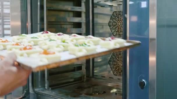 Профессиональный пекарь кладет сырую сладкую пекарню в духовку на коммерческой кухне — стоковое видео
