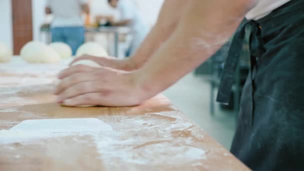 Panadero profesional está formando piezas de masa en la cocina comercial de panadería . — Vídeos de Stock