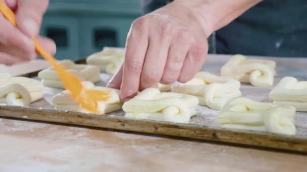 Bäcker schmiert die obere Oberfläche des süßen Backens vor dem Einzug in den Ofen — Stockvideo