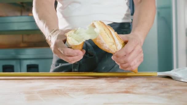 Bäcker zerreißt frisches Brot auf einer Hälfte. Männliche Hände brechen Baguette. — Stockvideo