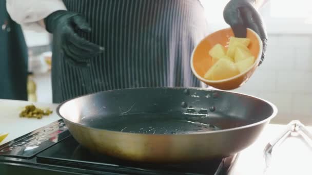 Professionele chef-kok legt een gehakte aardappel in koekenpan op commerciële keuken — Stockvideo