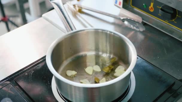 La mano del cocinero en los guantes pone el guisante en la cacerola de salsa con la cocción del ajo picado — Vídeos de Stock