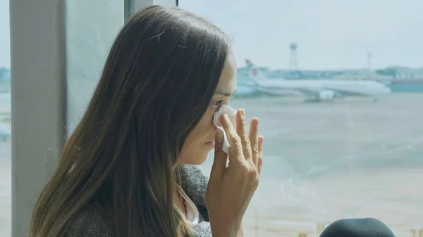 Jovem triste mulher está chorando no aeroporto com avião no fundo — Fotografia de Stock