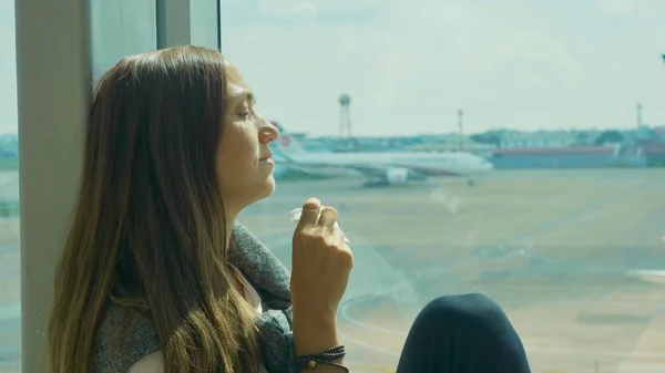 Unga ledsen kvinnan gråter på flygplats med flygplan på bakgrunden — Stockfoto