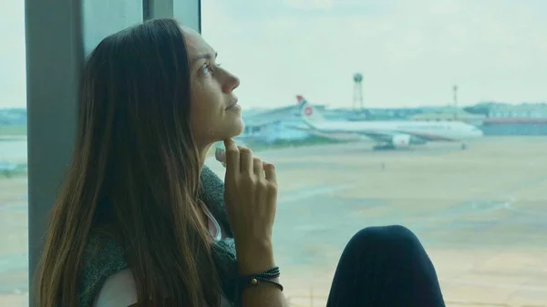 Unga ledsen kvinnan gråter på flygplats med flygplan på bakgrunden — Stockfoto