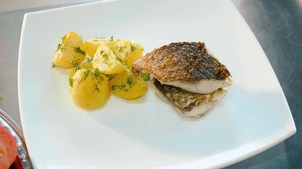 Prato de batatas preparadas com ervas e peixe em prato branco — Fotografia de Stock