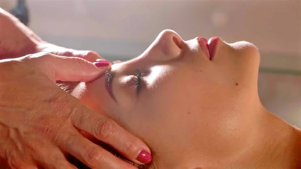 Masajista hace masaje en la cabeza para la mujer joven y bonita en el salón de spa, primer plano — Foto de Stock