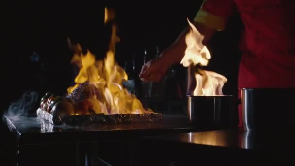 Nahaufnahme des Küchenchefs, der ein Hauptgericht für das Bankett zubereitet. Gemüse und Fleisch mit Feuershow — Stockvideo