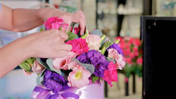 Florist girl makes a floral box in a flower salon, close-up