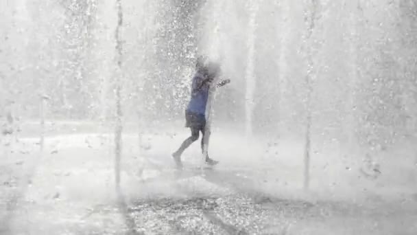 Wet little girl running and having fun in the jet fountain at city public park. — Stock Video