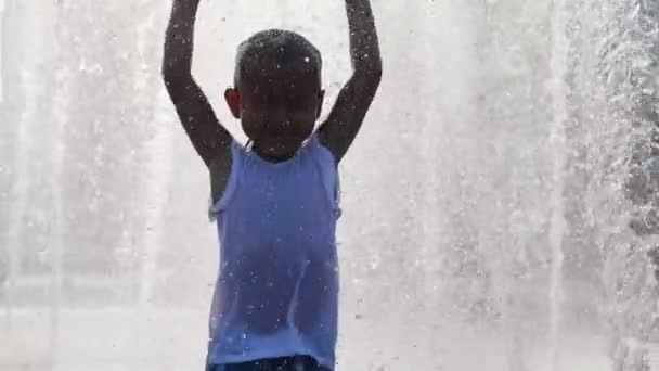 Мокрая маленькая девочка бегает и веселится в реактивном фонтане в городском общественном парке . — стоковое видео