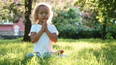 Çim yeşil yaz Park'ta küçük şirin bebek kız meditasyon.
