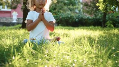 Çim yeşil yaz Park'ta küçük şirin bebek kız meditasyon.
