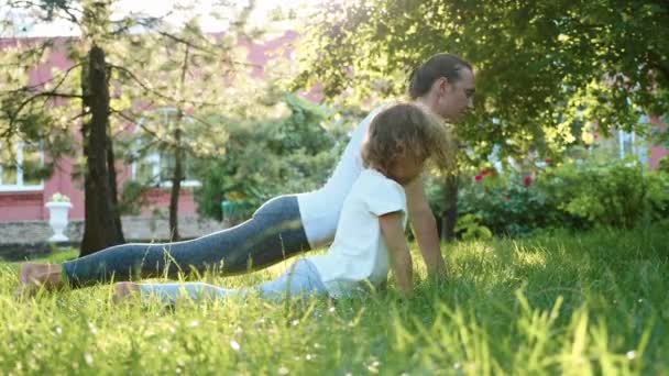 Mother and her little cute daughter doing yoga exercise together — Stock Video