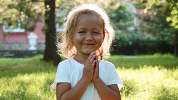 Kleines süßes Mädchen meditiert auf dem Rasen im grünen Sommerpark. — Stockvideo