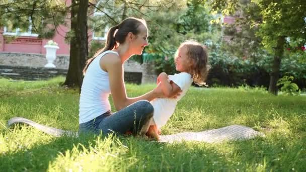 Familia feliz de joven madre deportiva y pequeña hija linda divirtiéndose al aire libre — Vídeos de Stock