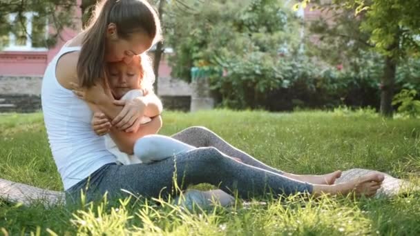 Familia feliz de joven madre deportiva y pequeña hija linda divirtiéndose al aire libre — Vídeos de Stock