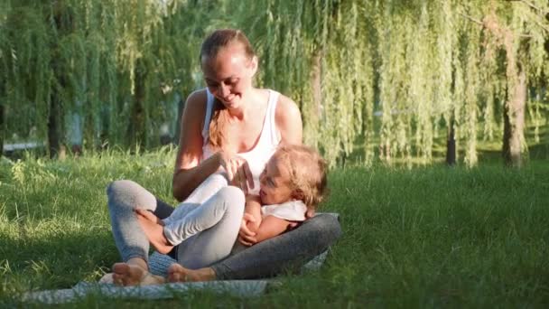 Familia feliz de joven madre deportiva y pequeña hija linda divirtiéndose al aire libre — Vídeo de stock