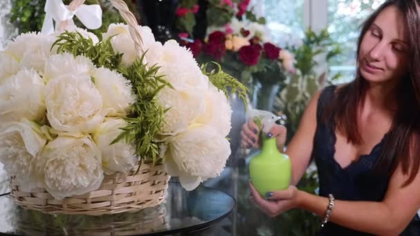 Floristería femenina joven rociando agua en ramo de flores en floristería, primer plano — Vídeo de stock