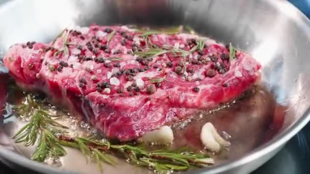 Bistecca di carne con condimenti ed erbe sibilanti sulla padella, primo piano — Video Stock